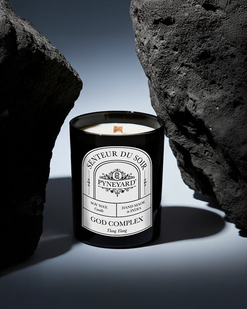 Pyneyard Ylang Ylang Scented Candle with a label in a dark setting known as god complex