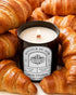 Pyneyard Apple Cinnamon Scented candle labeled 'Show Stopper' surrounded by croissants
