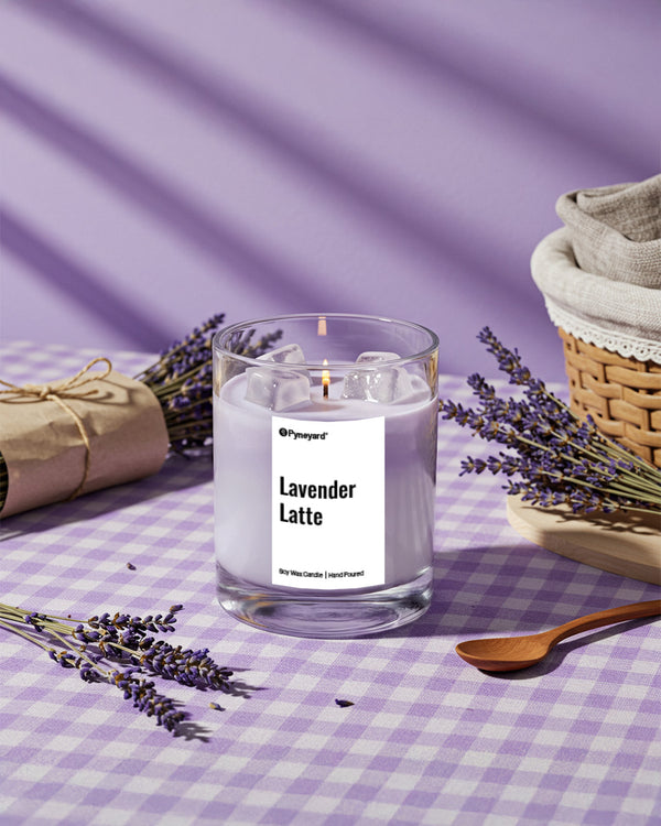 Pyneyard Candle labeled 'Lavender Latte' on a checkered tablecloth with lavender flowers.