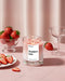 Pyneyard Candle labeled 'Strawberry Latte' with strawberries and a glass on a pink surface