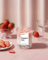 Pyneyard Candle labeled 'Strawberry Latte' with strawberries and a glass on a pink surface
